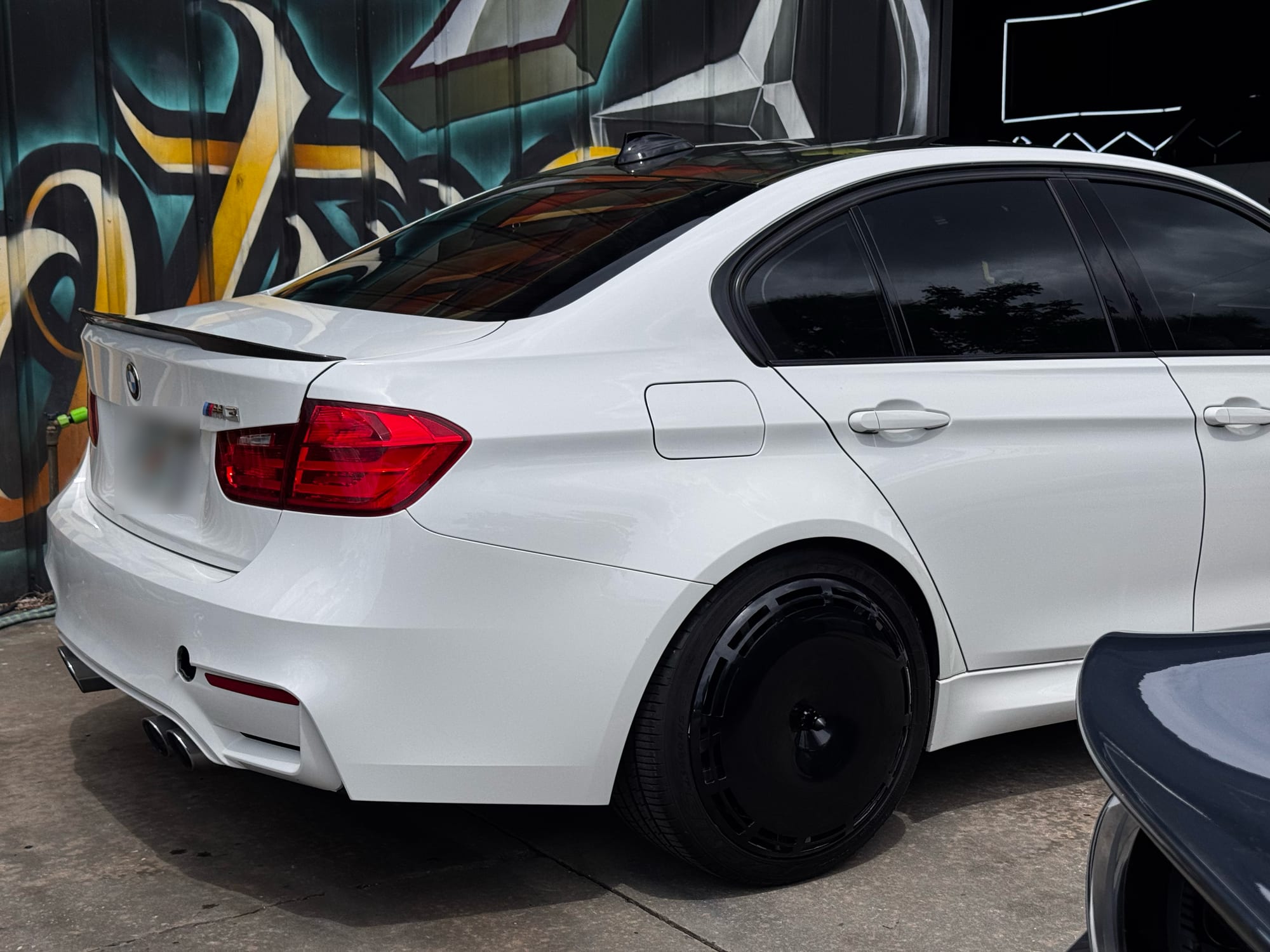 Rear quarter of a white BMW M3 with a gloss black Performance Series AIRODISC fitted to the rear wheel
