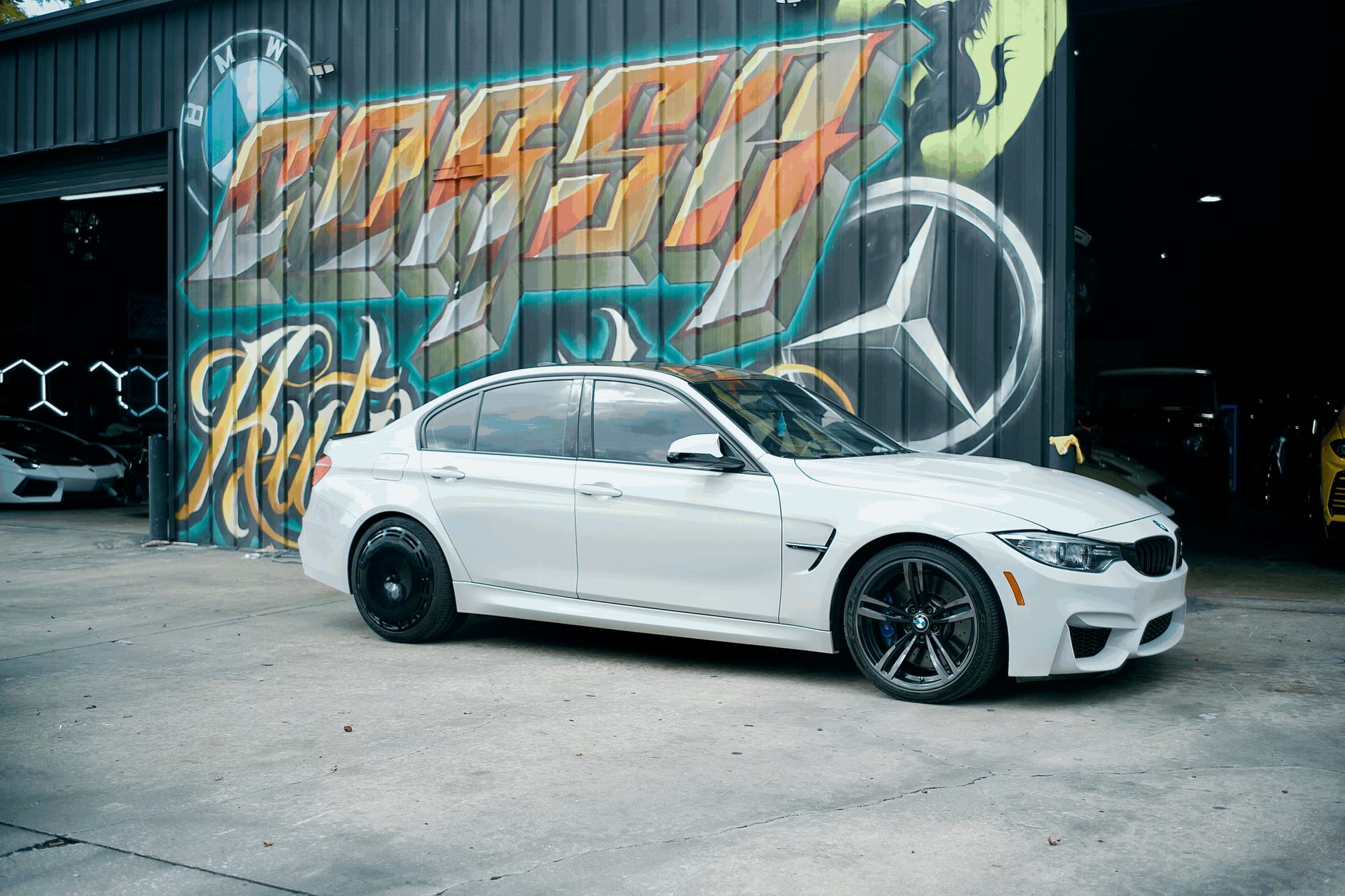 White BMW M3 photographed side on outside the Corsa Automotive shop, factory wheel on the front and a gloss black Performance Series AIRODISC on the rear
