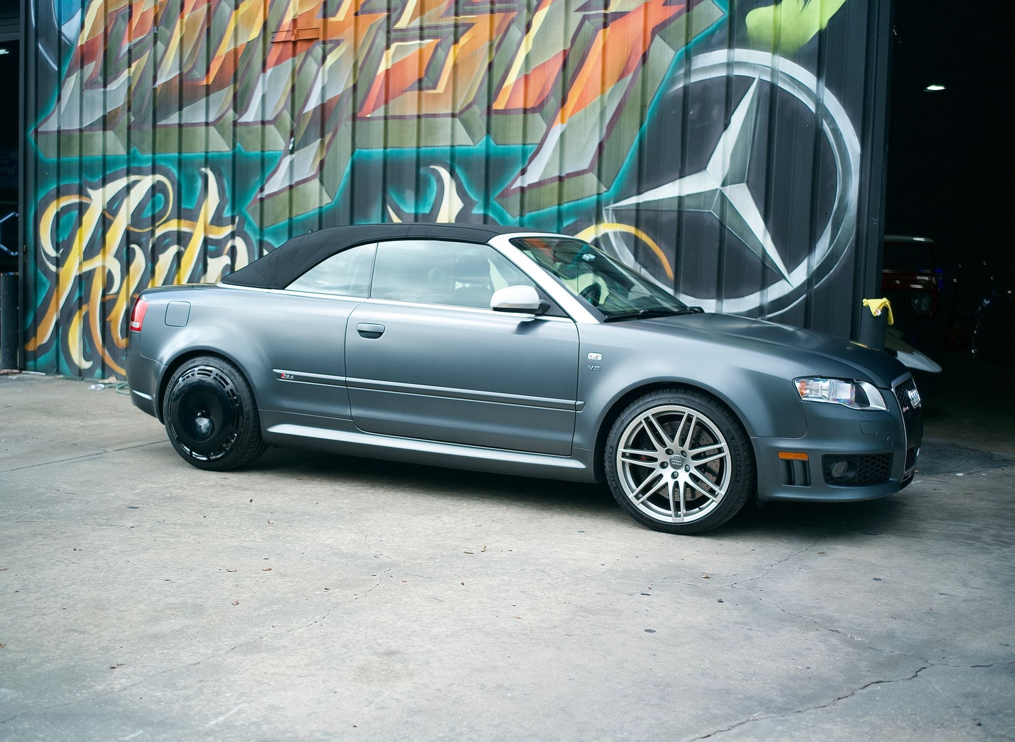 Matte grey Audi RS4 cabriolet photographed side on outside the Corsa Automotive shop, silver factory wheel on the front and a gloss black AIRODISC on the rear